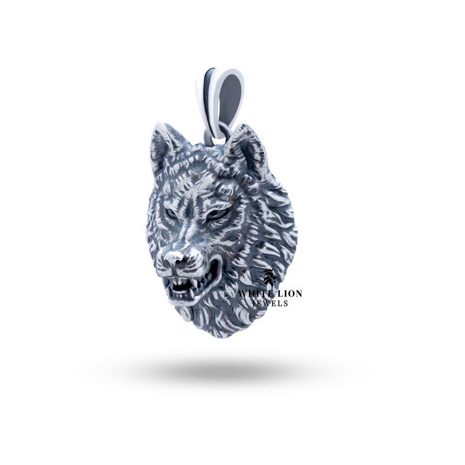 Display of the Angry Wolf Head Pendant in sterling silver on a dark background to accentuate design.